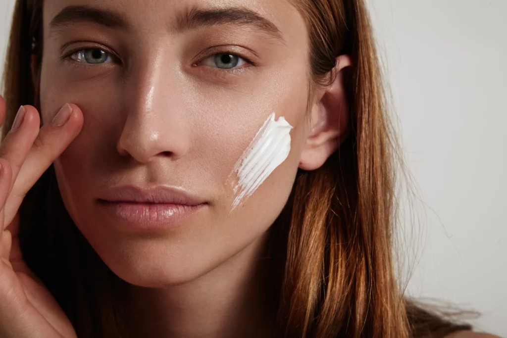 Woman with healthy, radiant skin and long brown hair, applying medical-grade skincare in Powell, WY.