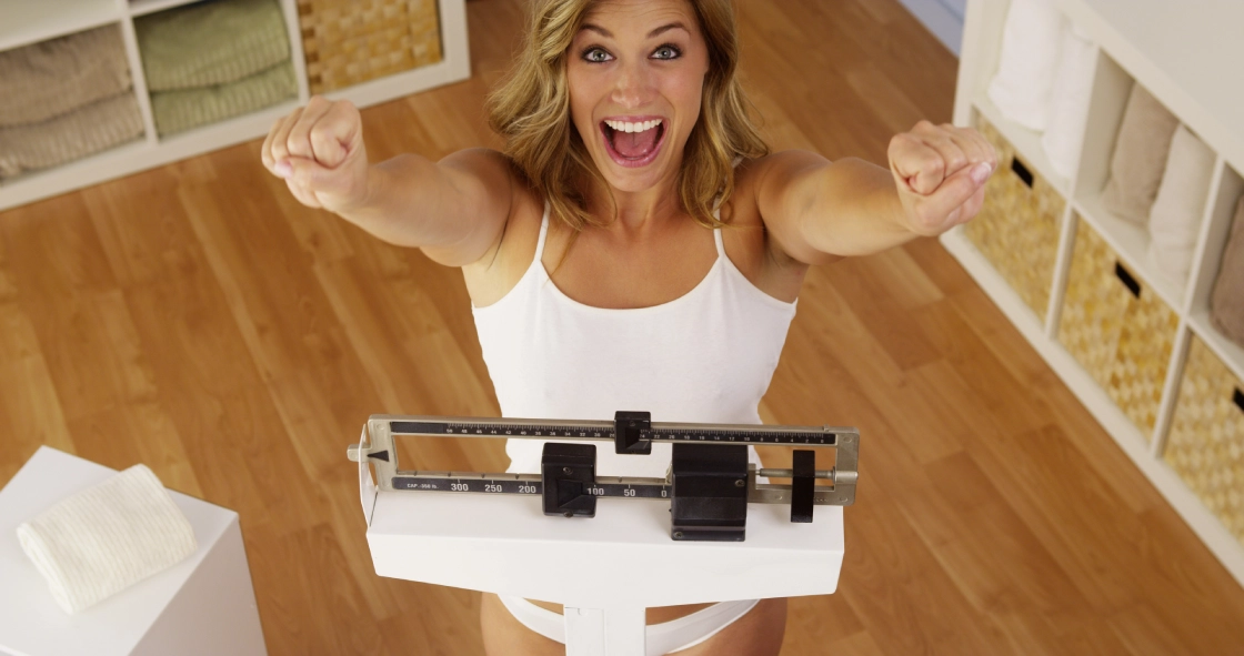 An excited woman celebrates her weight loss results on a medical scale in Powell. WY