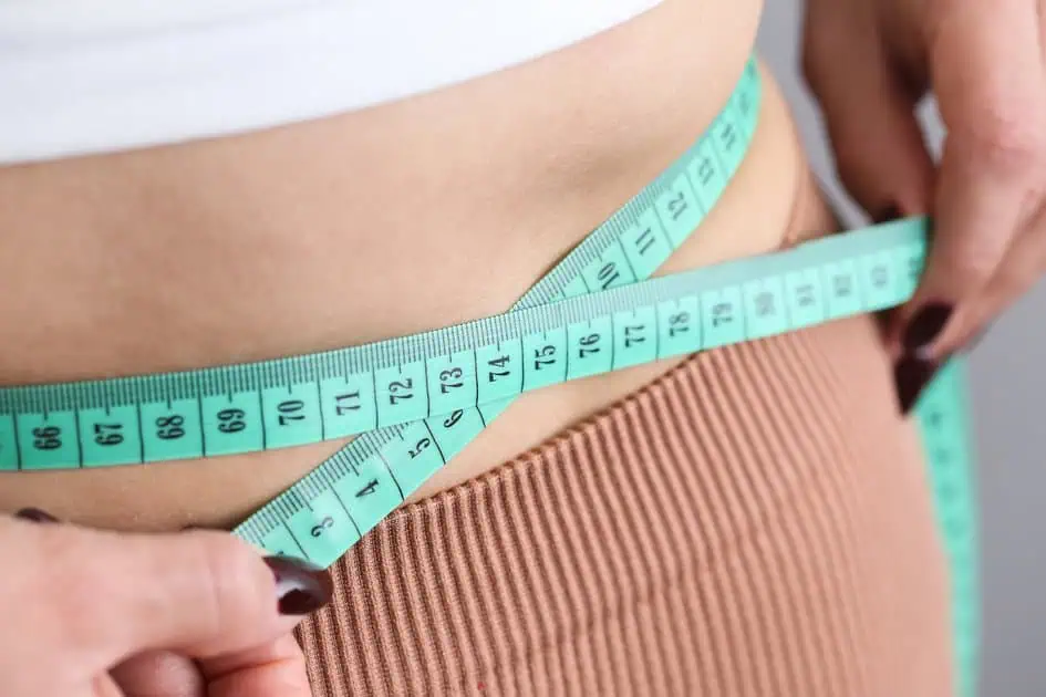 Person measuring waist with tape, promoting Weight Loss Programs in Powell, WY.