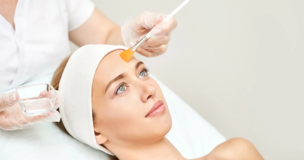Woman with headband gets a facial peel as therapist applies product to her forehead, representing Chemical Peels in Powell, WY.