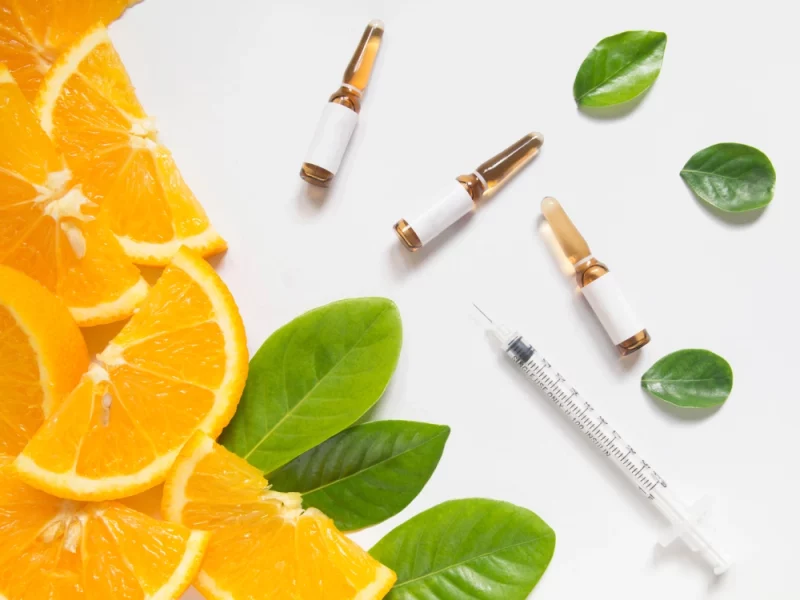 Orange slices, green leaves, vitamin ampoules, and a syringe symbolize IM Nutrient Therapy in Powell, WY.